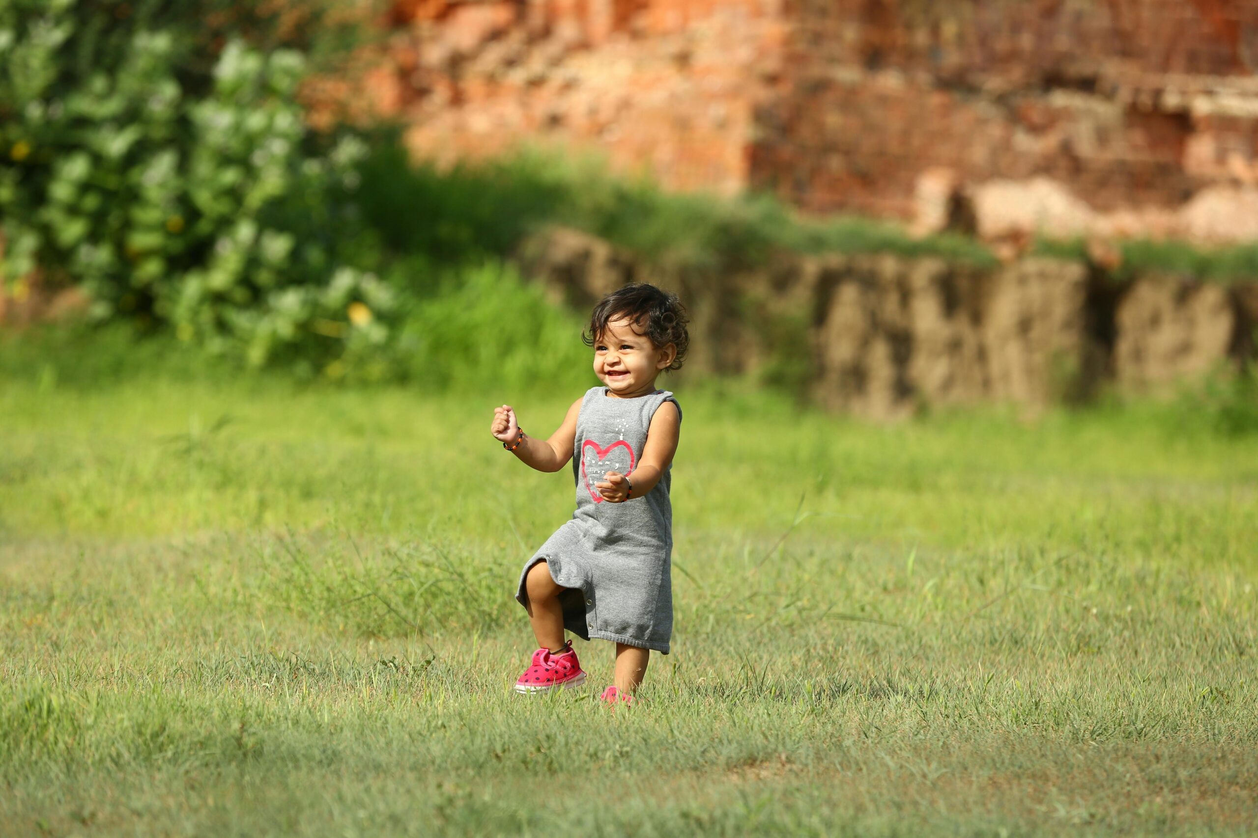 A happy child playing on a grassy field, embodying joy and innocence on a bright sunny day at Play school ground